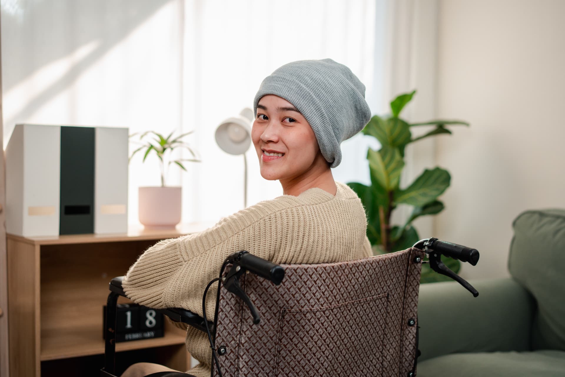 A young woman in a wheelchair smiling in a bright, comfortable home