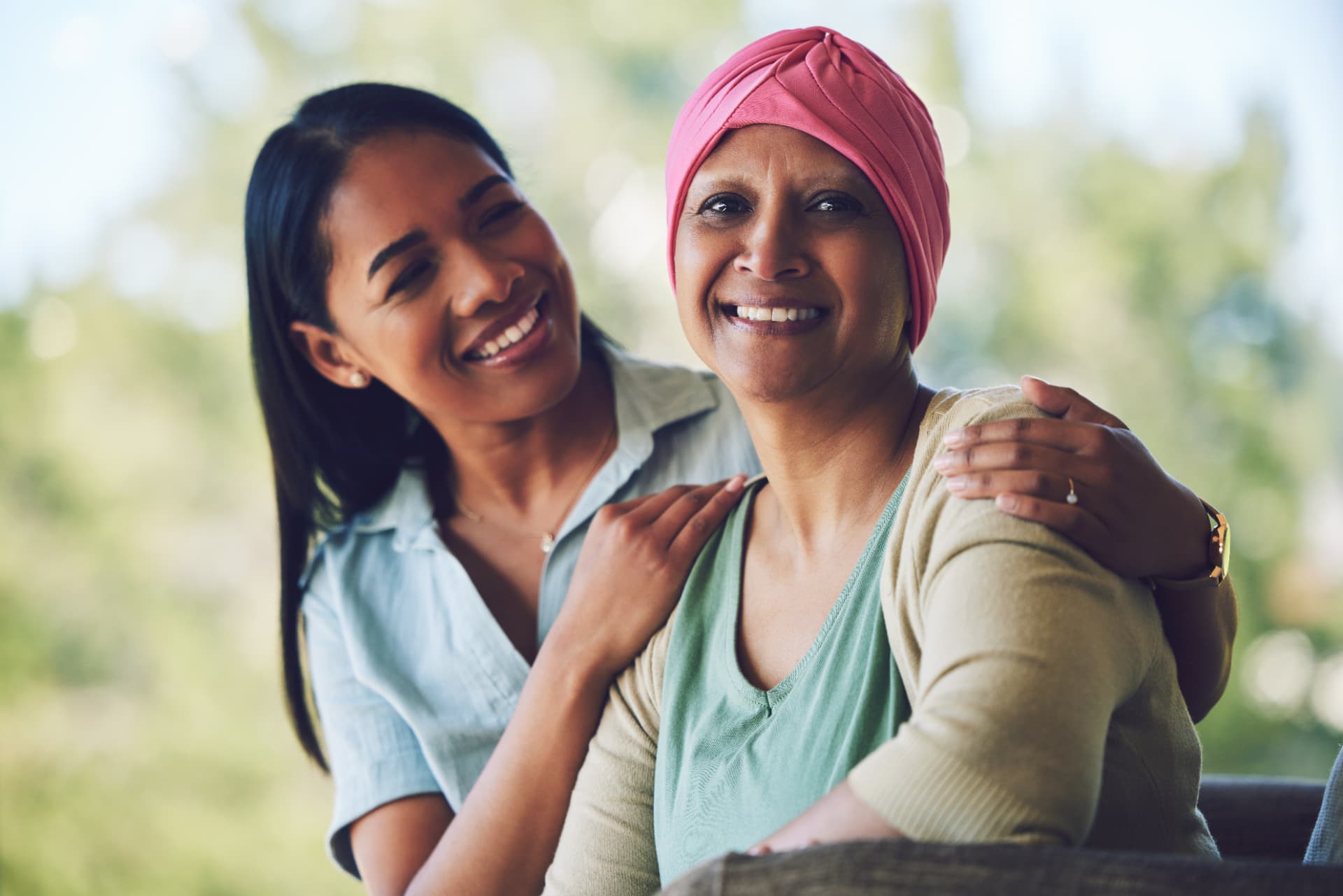 Two women sitting together, one resting a supportive hand on the other's shoulder